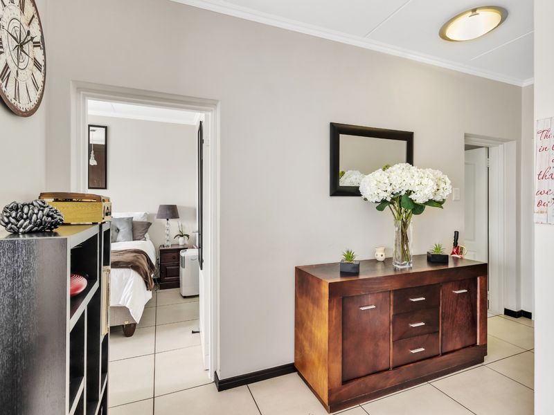 A bright and well-maintained hallway featuring neutral tiled flooring and coved ceilings, providing access to adjacent rooms.