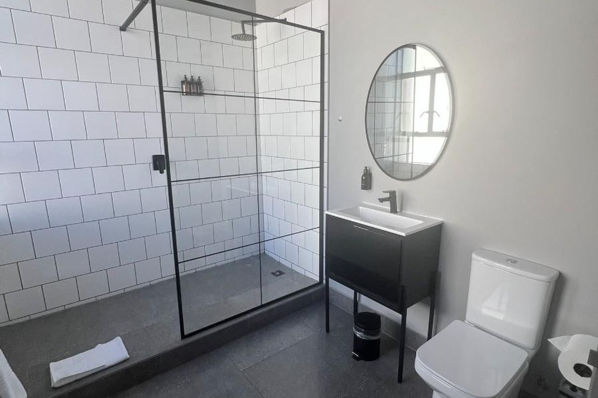 Modern bathroom featuring a walk-in shower with black-framed glass screen, subway tiling, vanity unit with basin, and a contemporary toilet.