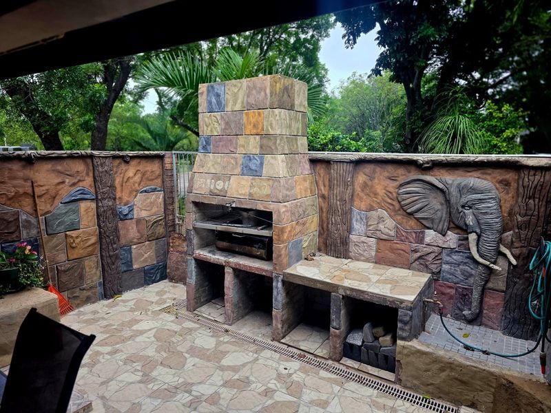 Outdoor patio area featuring a built-in braai, decorative stone-effect wall cladding, and tiled flooring, providing a functional space for outdoor entertaining.
