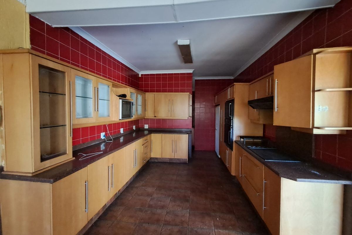 Spacious kitchen featuring extensive built-in cabinetry, granite countertops, and integrated appliances, offering a functional layout ready for modernization.