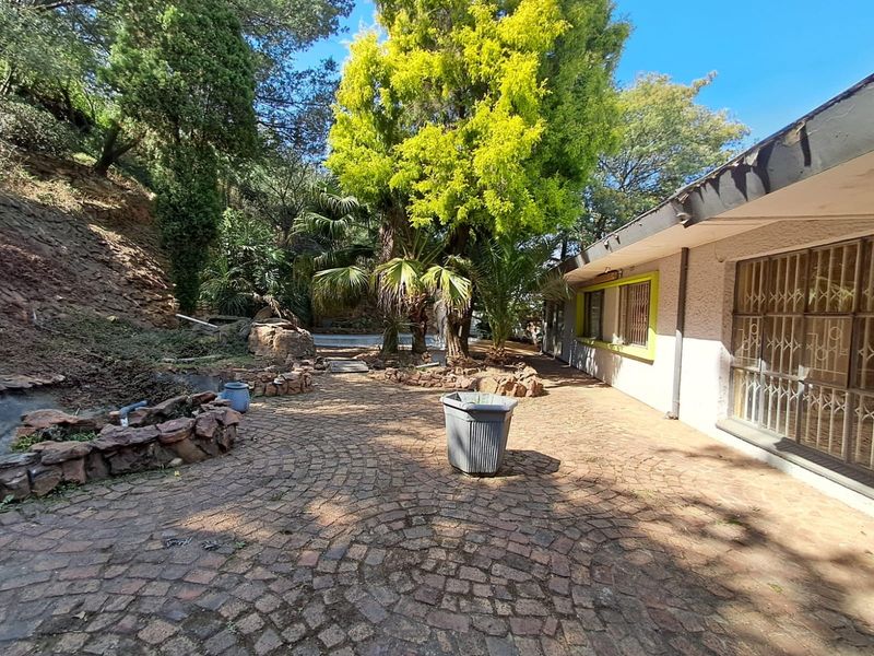 Rear exterior view featuring a paved patio area, established garden, and security bars on the windows.