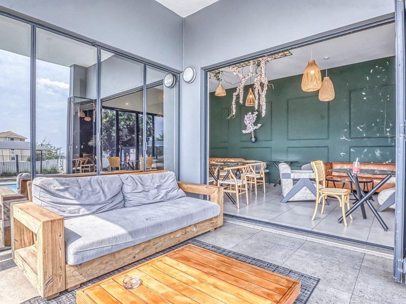 A spacious covered patio featuring large folding glass doors that seamlessly connect the outdoor area to the interior living space.