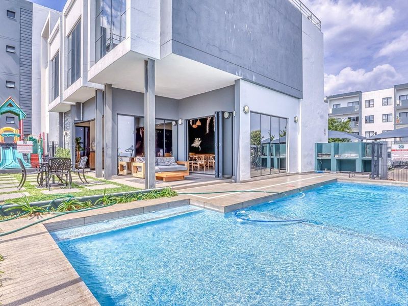 Modern apartment exterior featuring a private swimming pool, paved patio area, and seamless indoor-outdoor flow through large bi-fold doors.