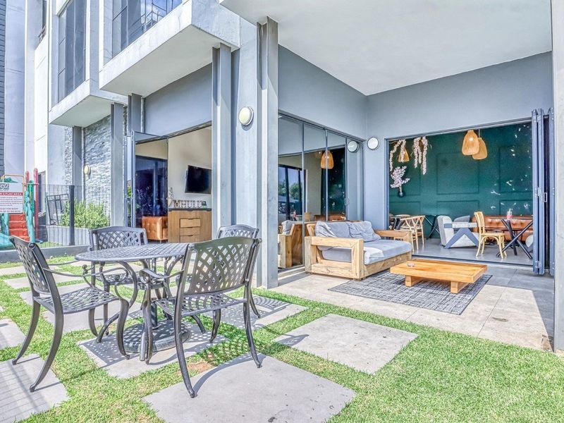 A modern ground-floor patio featuring large bi-fold glass doors that seamlessly connect the outdoor tiled entertainment area to the interior living space.