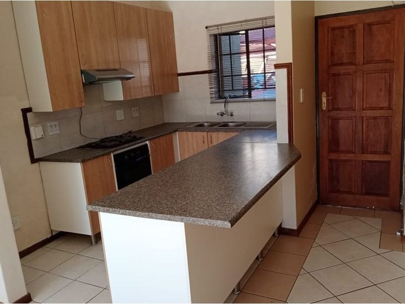 A functional kitchen featuring built-in cabinetry, laminate countertops, integrated oven and hob, and tiled flooring, offering a practical layout for daily use.