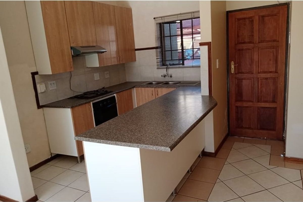 A functional kitchen featuring built-in cabinetry, laminate countertops, integrated oven and hob, and tiled flooring, offering a practical layout for daily use.