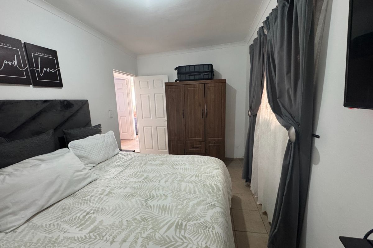 A functional bedroom featuring tiled flooring, coved ceilings, and a standard panel door, providing a neutral base for potential interior updates.