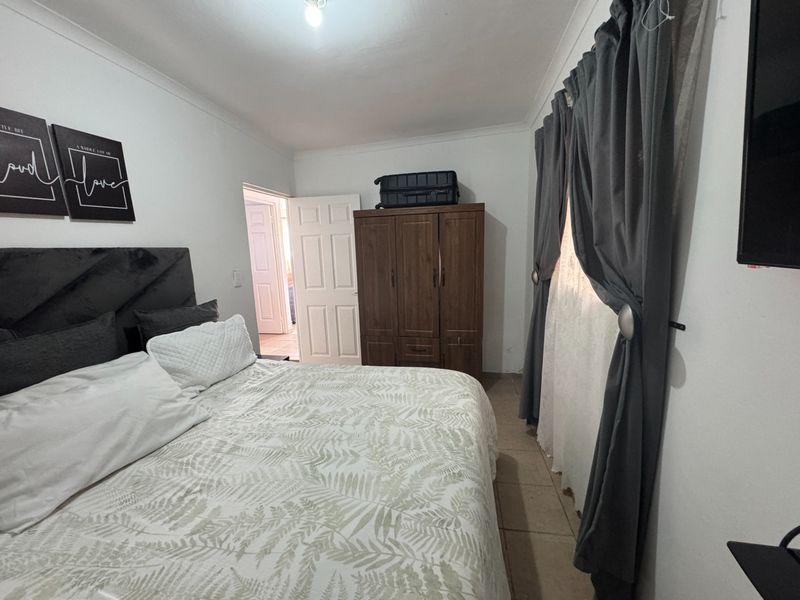 A functional bedroom featuring tiled flooring, coved ceilings, and a standard panel door, providing a neutral base for potential interior updates.