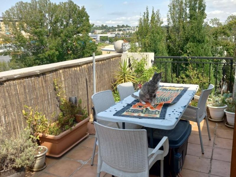 An outdoor balcony featuring tiled flooring, a metal safety railing, and a bamboo privacy screen, offering an open-air space with elevated views.