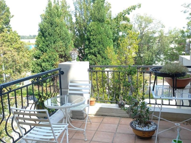 A private balcony featuring tiled flooring and a decorative wrought iron railing, offering an elevated outdoor space with surrounding greenery.