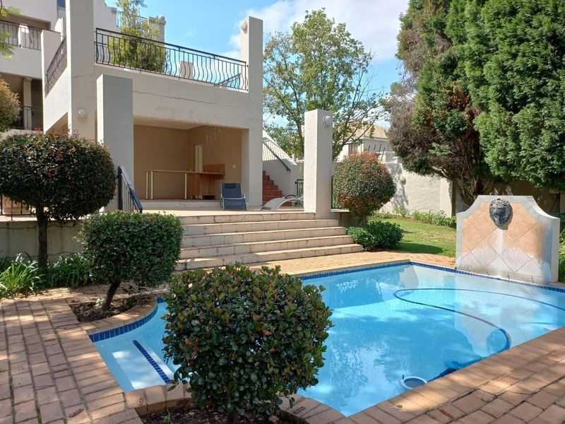Outdoor pool area featuring a swimming pool, brick paving, a stone water feature, and a covered patio with stairs leading to the upper level.