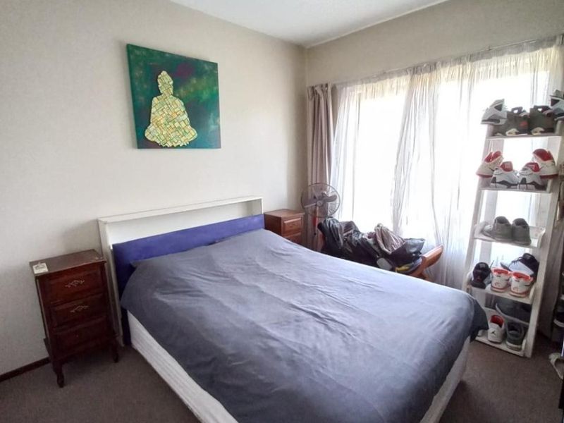 A standard bedroom featuring carpeted flooring and a central ceiling light fixture, offering a functional space with natural light from the window.