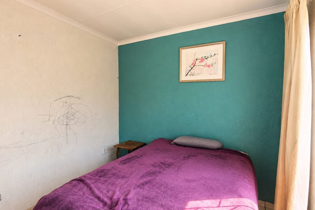A bedroom featuring a teal accent wall and a white wall with visible surface damage, requiring cosmetic attention.