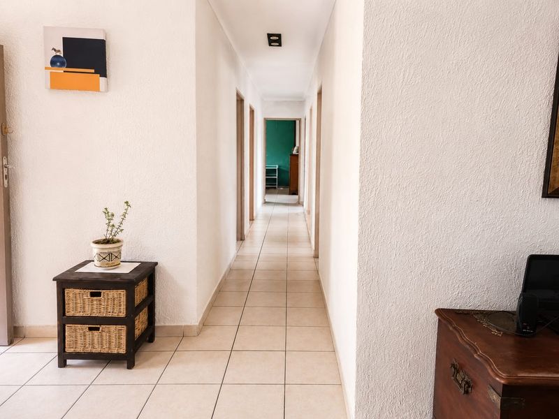 A bright, tiled hallway providing access to multiple rooms, featuring neutral walls and recessed ceiling lighting.