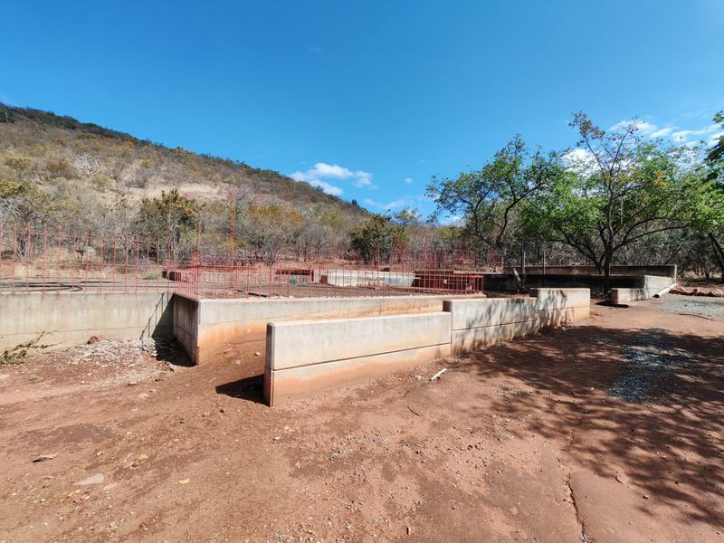 An outdoor area featuring concrete retaining walls and exposed steel reinforcement mesh, indicating an incomplete construction or landscaping project.