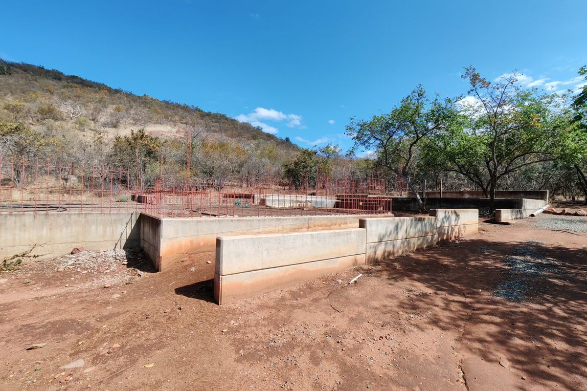An outdoor area featuring concrete retaining walls and exposed steel reinforcement mesh, indicating an incomplete construction or landscaping project.