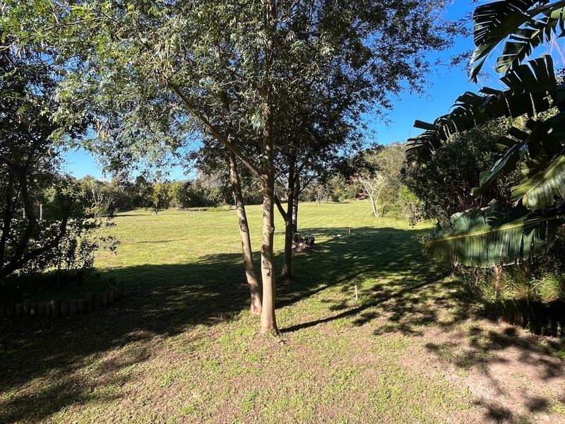 A spacious, well-maintained residential garden area featuring mature trees and open lawn space, offering a peaceful outdoor setting.