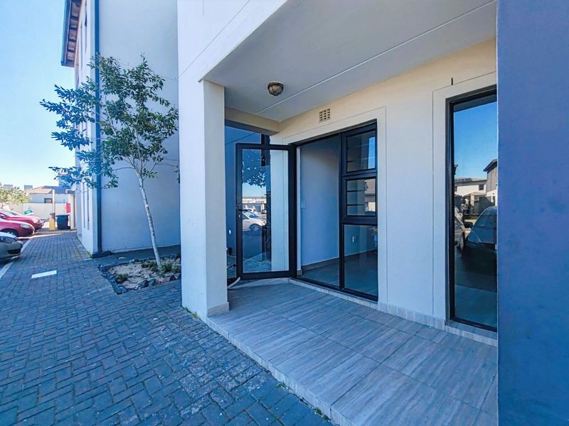 A covered ground-floor patio area featuring modern tiled flooring and aluminium-framed glass doors providing access to the apartment interior.