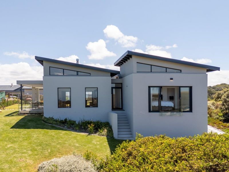 Modern architectural home featuring a striking skillion roof design, clerestory windows, and a spacious covered patio overlooking a well-maintained garden.