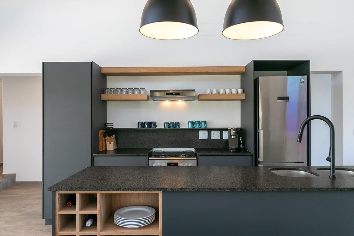 Modern kitchen featuring dark grey cabinetry, stone countertops, a central island with integrated wine storage, and high-quality built-in appliances.