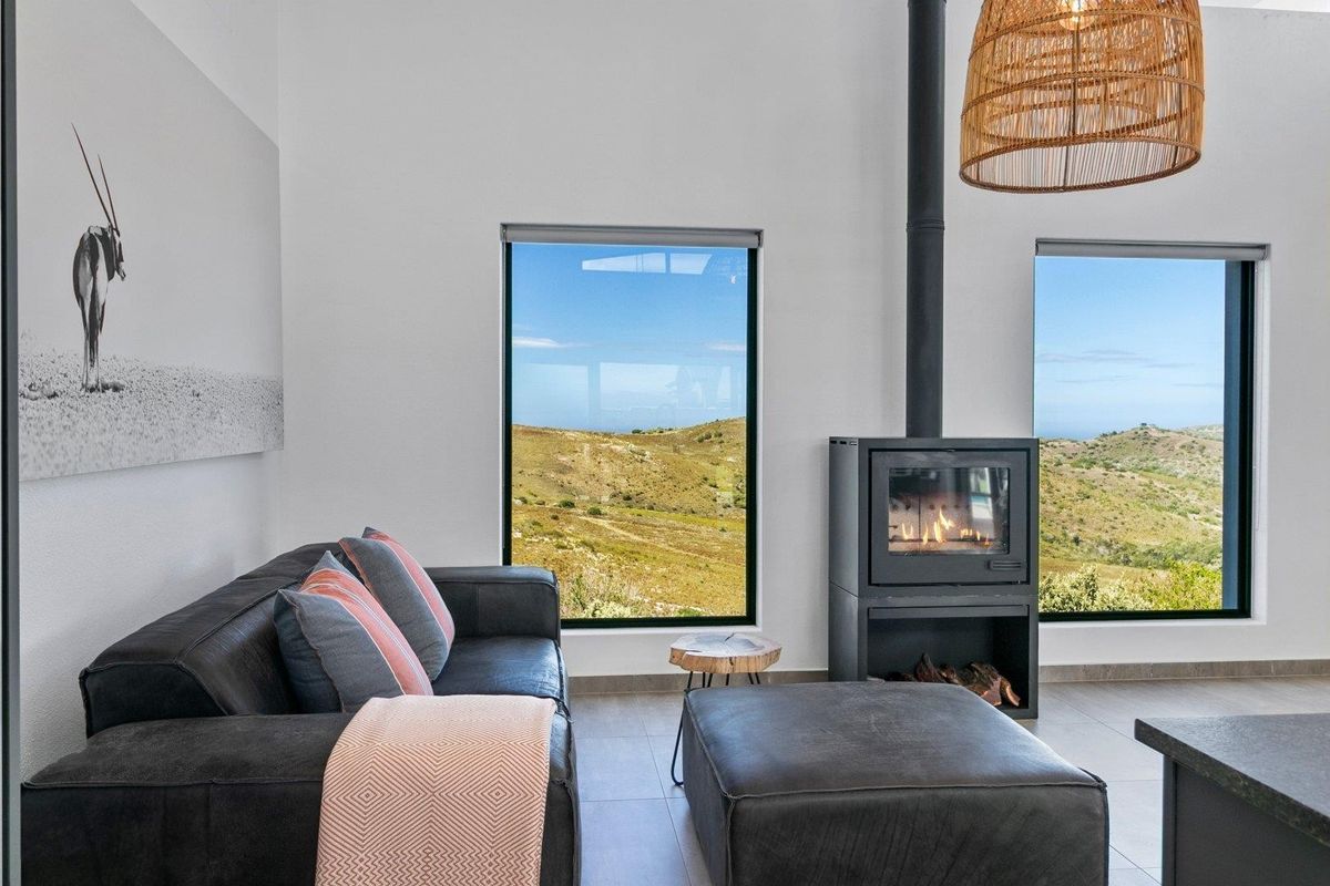 Modern living room featuring a sleek freestanding fireplace, large windows with scenic landscape views, and high-quality tiled flooring.