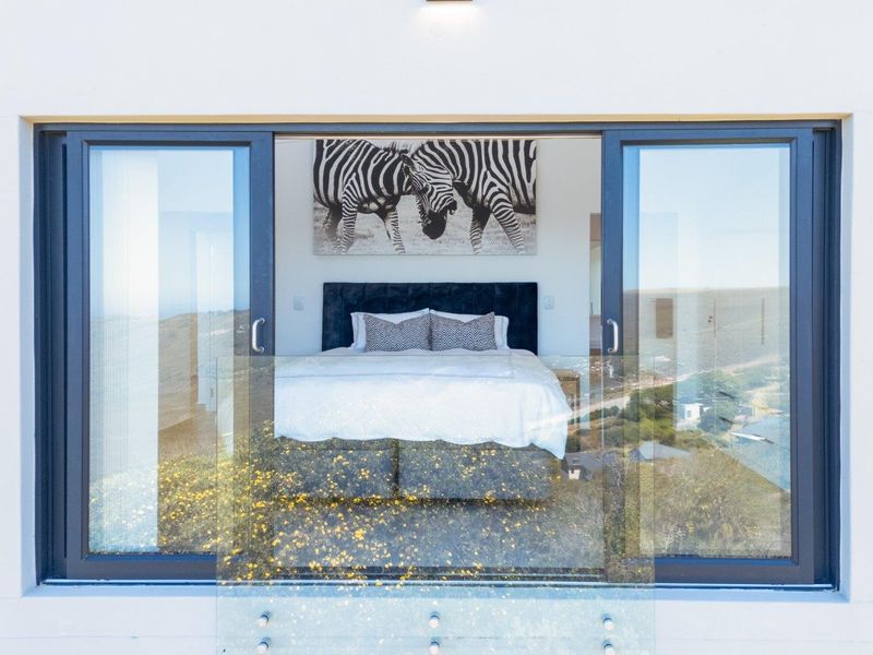 A modern bedroom featuring large sliding glass doors that open to a glass balustrade, offering expansive views.