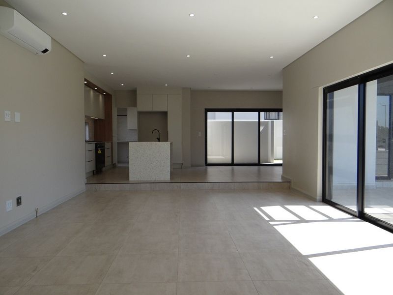 Spacious open-plan living and kitchen area featuring modern cabinetry, a central island, tiled floors, and large sliding doors leading to the exterior.