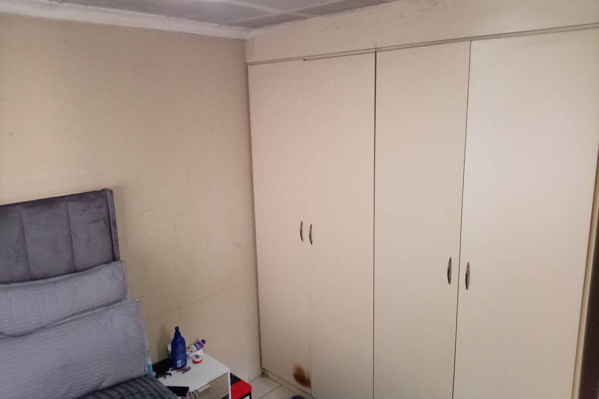 A bedroom featuring built-in cupboards with some visible wear and scuffed wall finishes, offering potential for cosmetic updates.