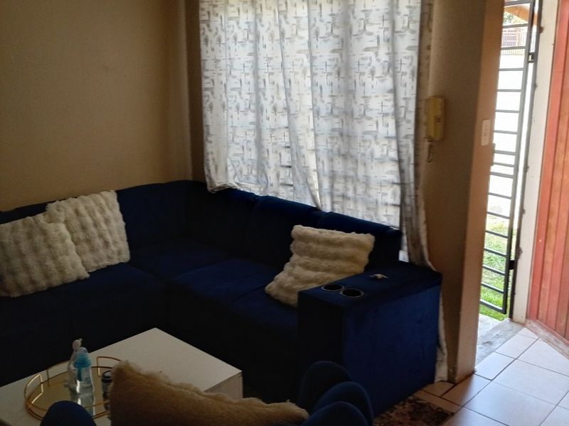 A living room area featuring tiled flooring, a security gate at the entrance, and neutral wall finishes.