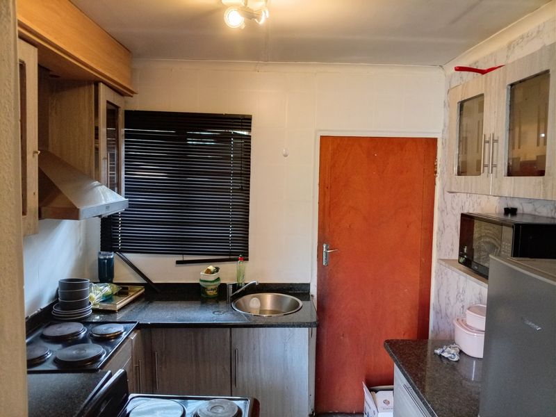 A functional kitchen featuring granite countertops, built-in cabinetry, an electric hob, and an extractor fan, offering a practical layout for daily meal preparation.