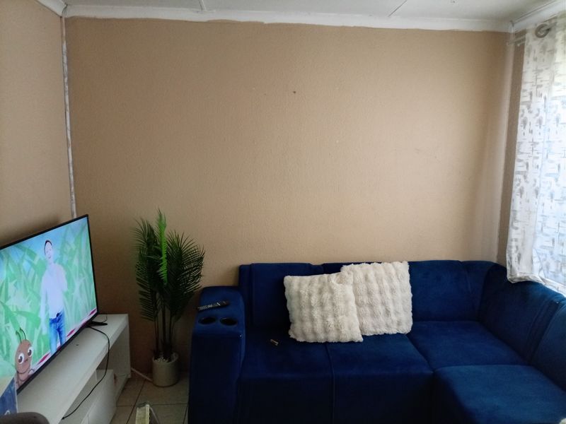 A living room space featuring tiled flooring and simple cornicing, currently finished with plain wall surfaces.