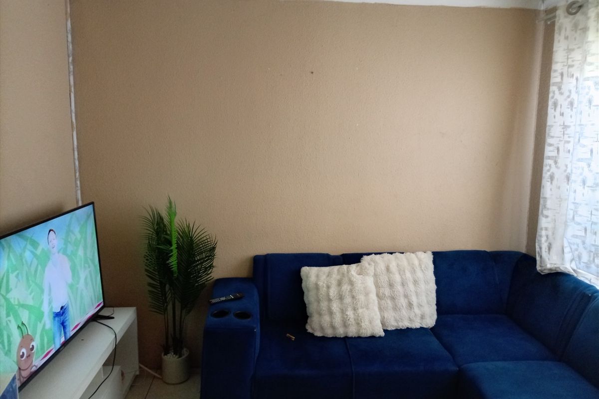 A living room space featuring tiled flooring and simple cornicing, currently finished with plain wall surfaces.