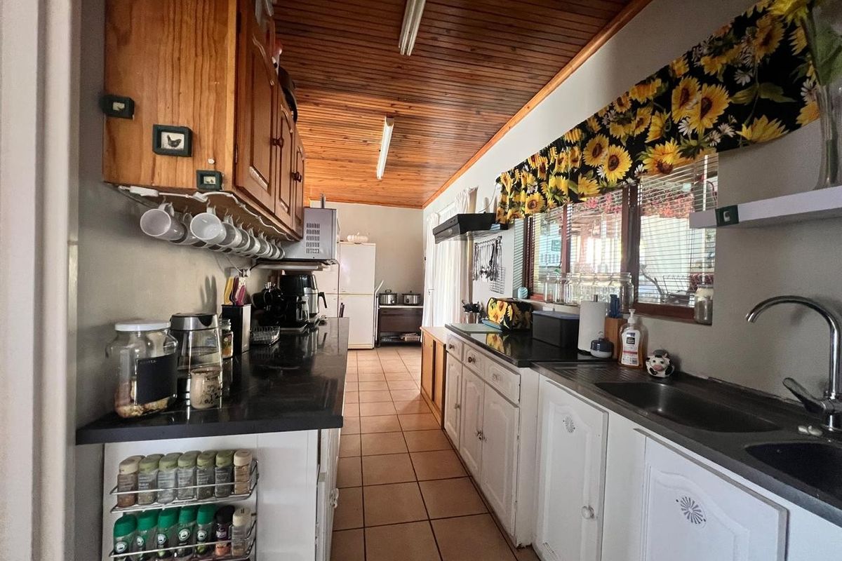 A functional galley-style kitchen featuring wooden ceilings, tiled floors, and ample built-in cabinetry with dark countertops.