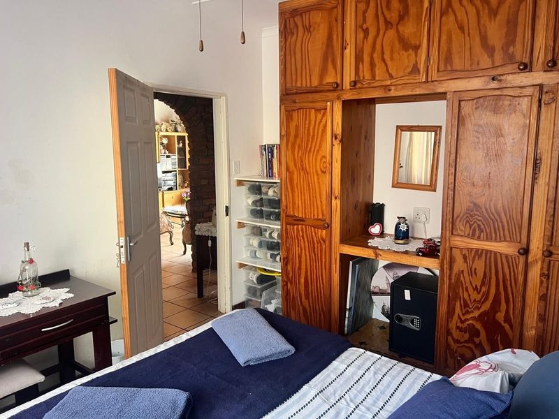 A bedroom featuring a large built-in wooden wardrobe and an arched doorway leading to an adjacent living space.