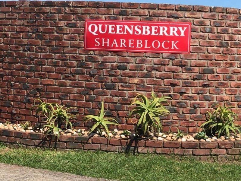 A view of the property entrance featuring a face brick boundary wall with signage.