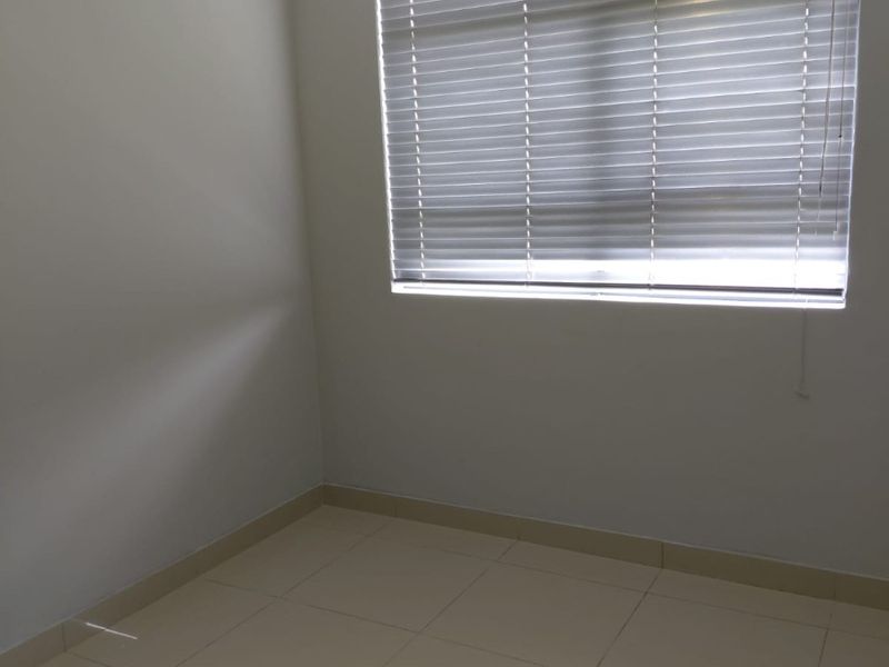 A clean, empty bedroom featuring neutral tiled flooring, crisp wall finishes, and fitted venetian blinds, offering a versatile space ready for personalization.
