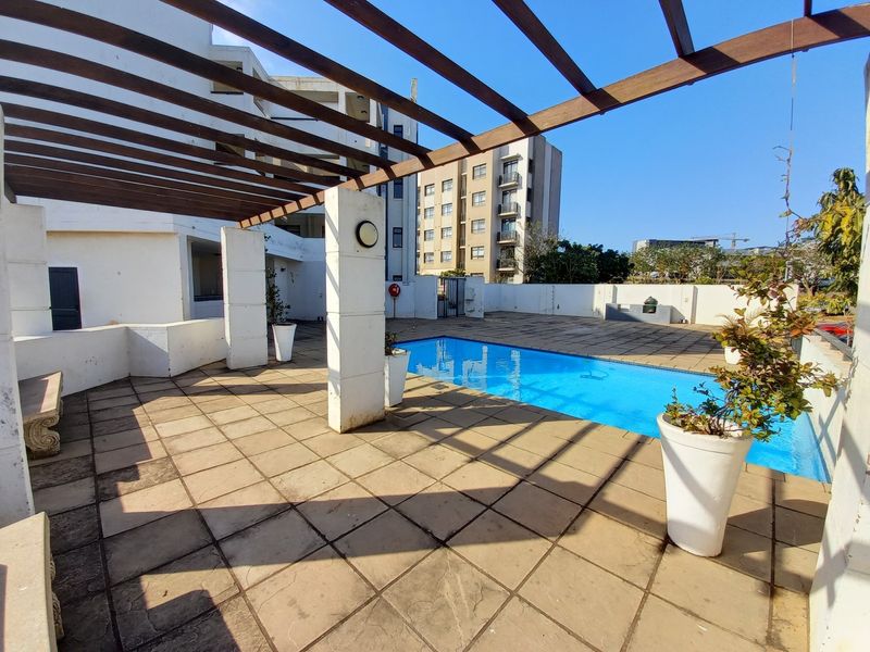 Outdoor pool area featuring a swimming pool, paved patio, and a timber pergola structure.