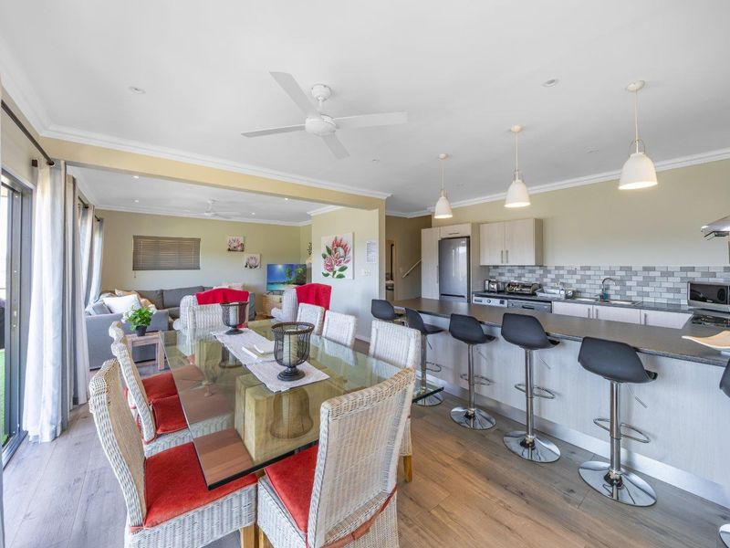 Spacious open-plan living, dining, and kitchen area featuring modern cabinetry, a breakfast bar, recessed lighting, and direct access to the outdoor patio.