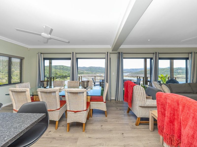 Spacious open-plan living and dining area featuring laminate flooring, ceiling fans, and large sliding doors that open to scenic landscape views.