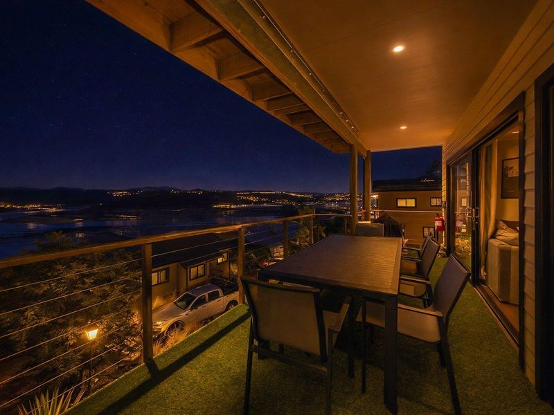 Covered balcony featuring recessed lighting, metal balustrade, and sliding door access, offering expansive night views over the surrounding landscape.
