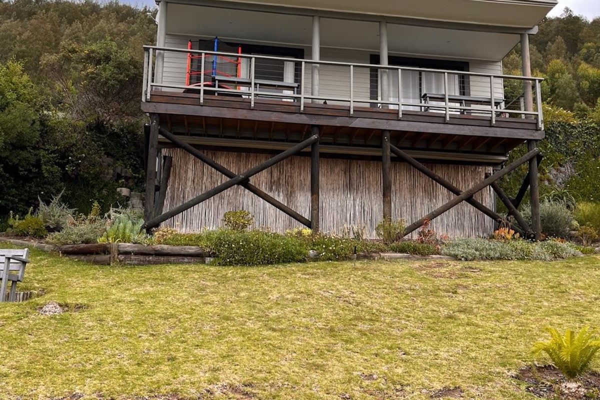Rear view of a multi-level residential property featuring timber balconies, sliding glass doors, and a landscaped garden area.