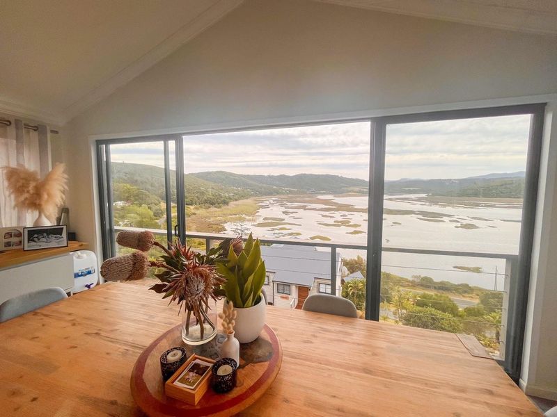 A bright living area featuring large sliding glass doors that open to a balcony, offering expansive views of the surrounding landscape and water.