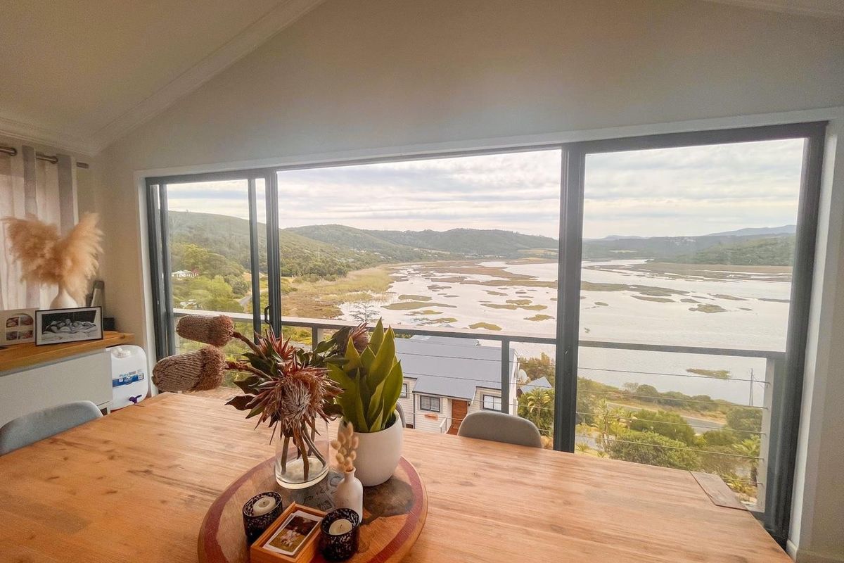 A bright living area featuring large sliding glass doors that open to a balcony, offering expansive views of the surrounding landscape and water.