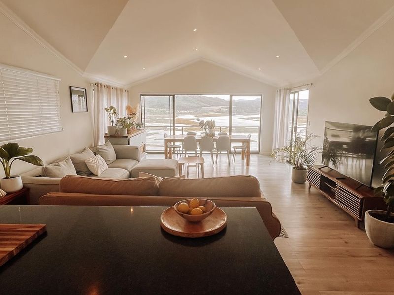 Spacious open-plan living and dining area featuring a high vaulted ceiling, modern kitchen island with granite countertop, and large sliding doors with scenic views.