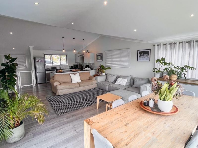Spacious open-plan living and dining area featuring modern laminate flooring, recessed lighting, and a functional kitchen with a central island.