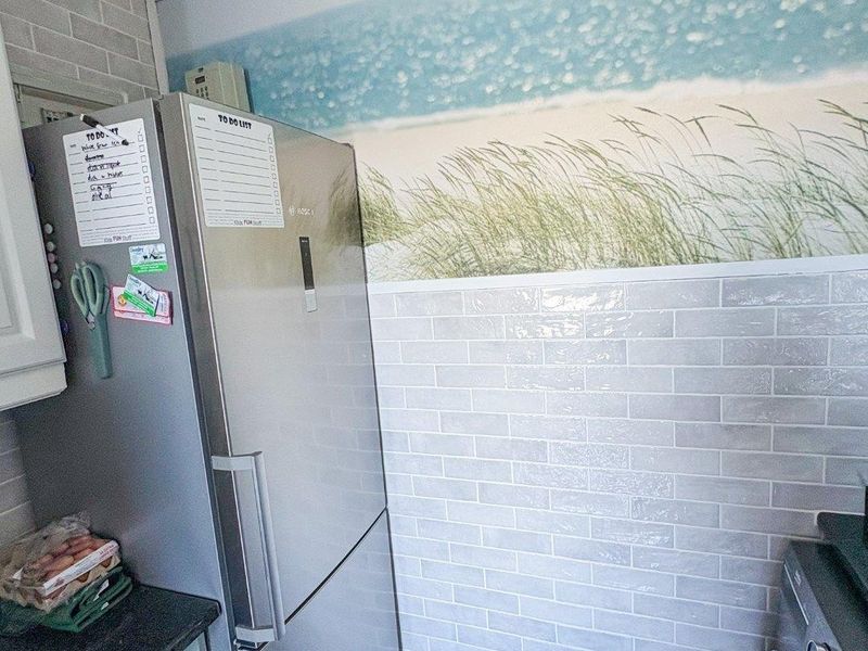 Kitchen area featuring a subway tile backsplash, light wood-look flooring, and decorative wall mural.