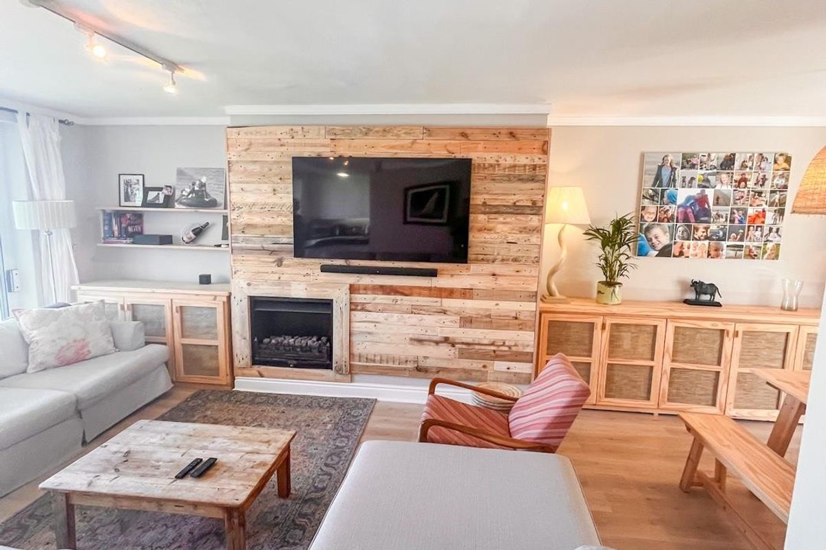 Spacious living room featuring a prominent timber-clad feature wall with a built-in fireplace and light wood-look flooring.