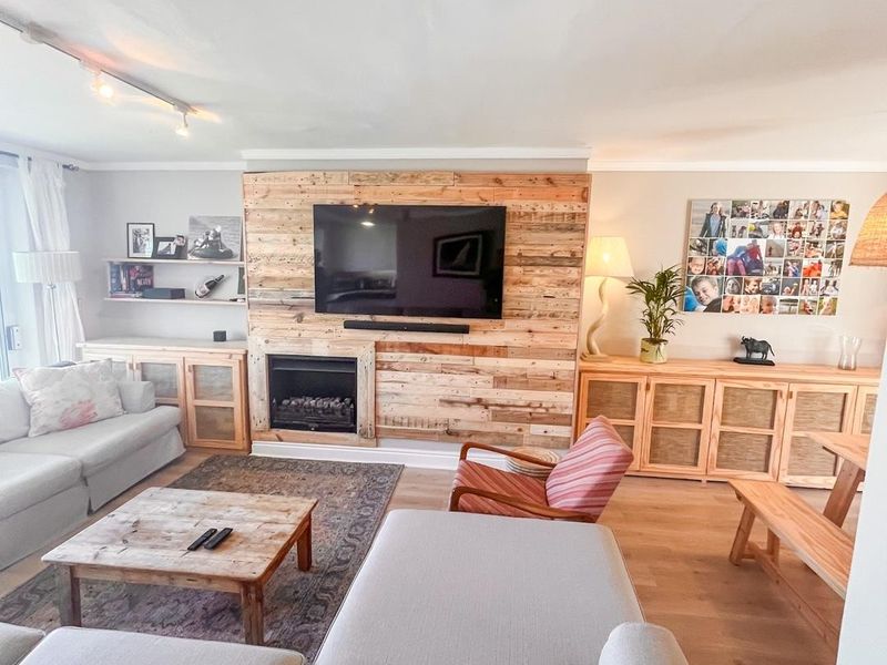 Spacious living room featuring a prominent timber-clad feature wall with a built-in fireplace and light wood-look flooring.