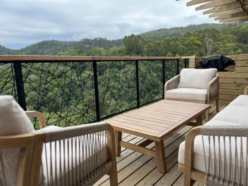 A well-maintained timber balcony featuring a modern black metal balustrade and scenic forest views.
