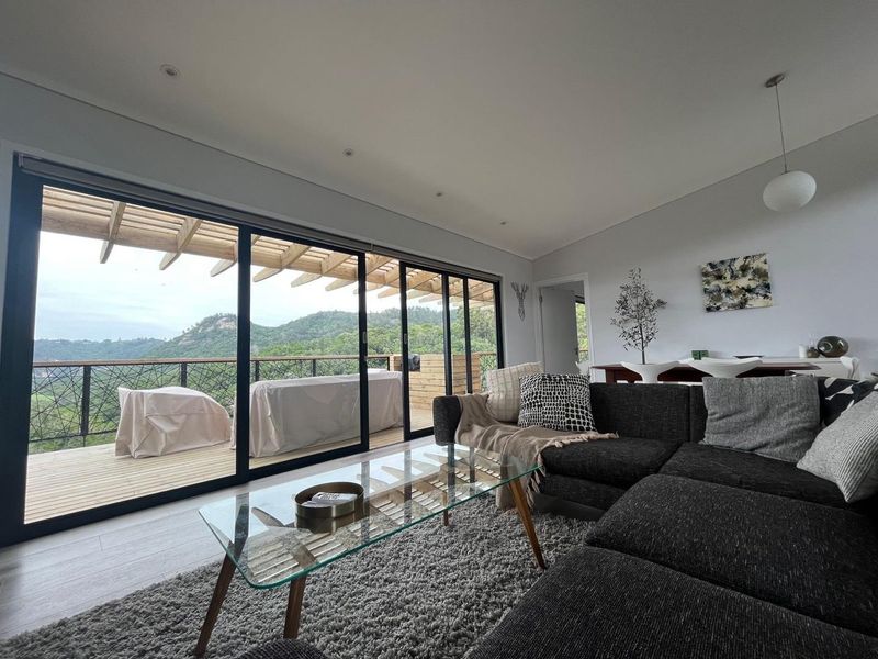 Spacious living room featuring large sliding glass doors that open onto a timber deck with scenic mountain views.